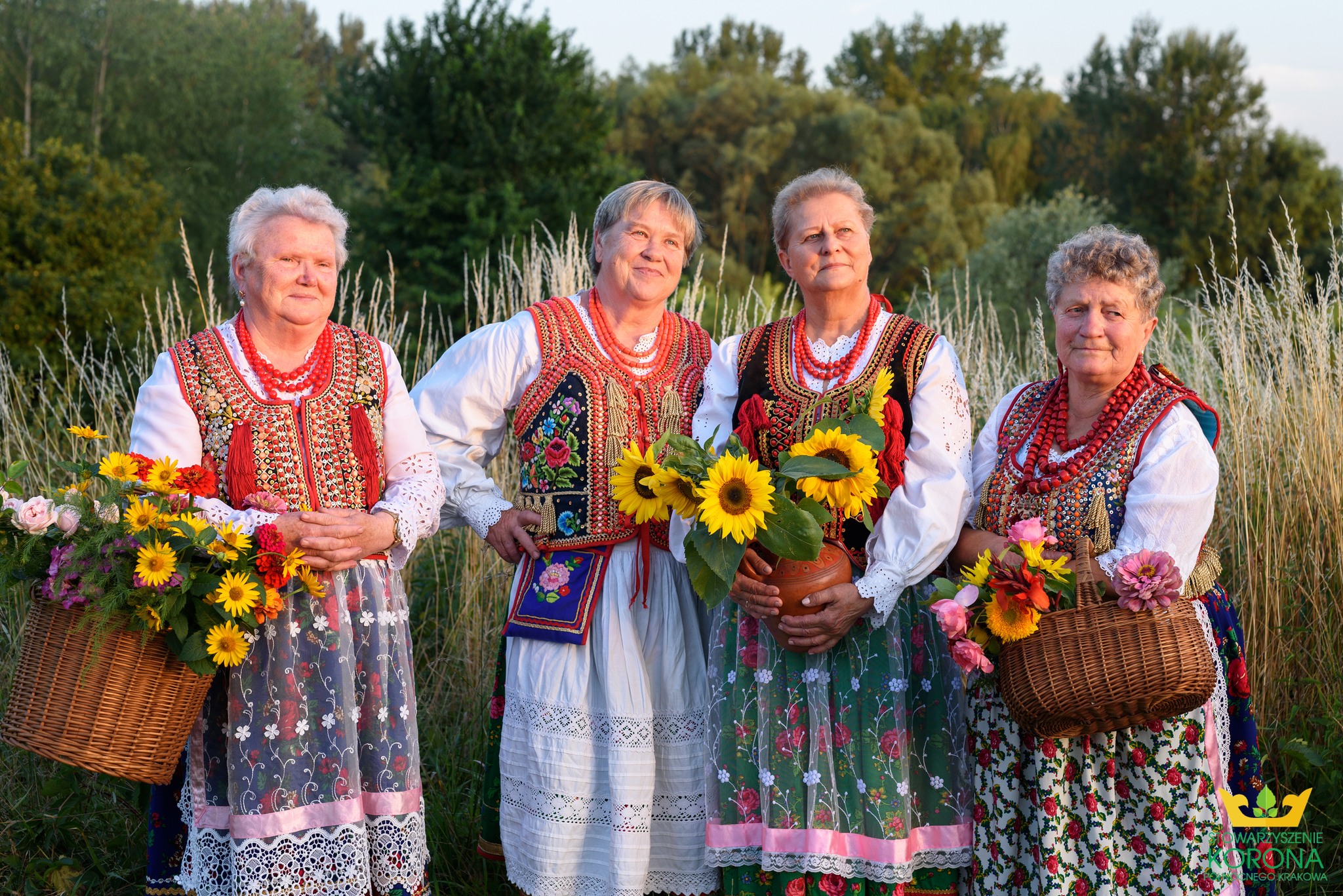 zdjęcie przedstawia cztery kobiety w strojach krakowskich w plenerze