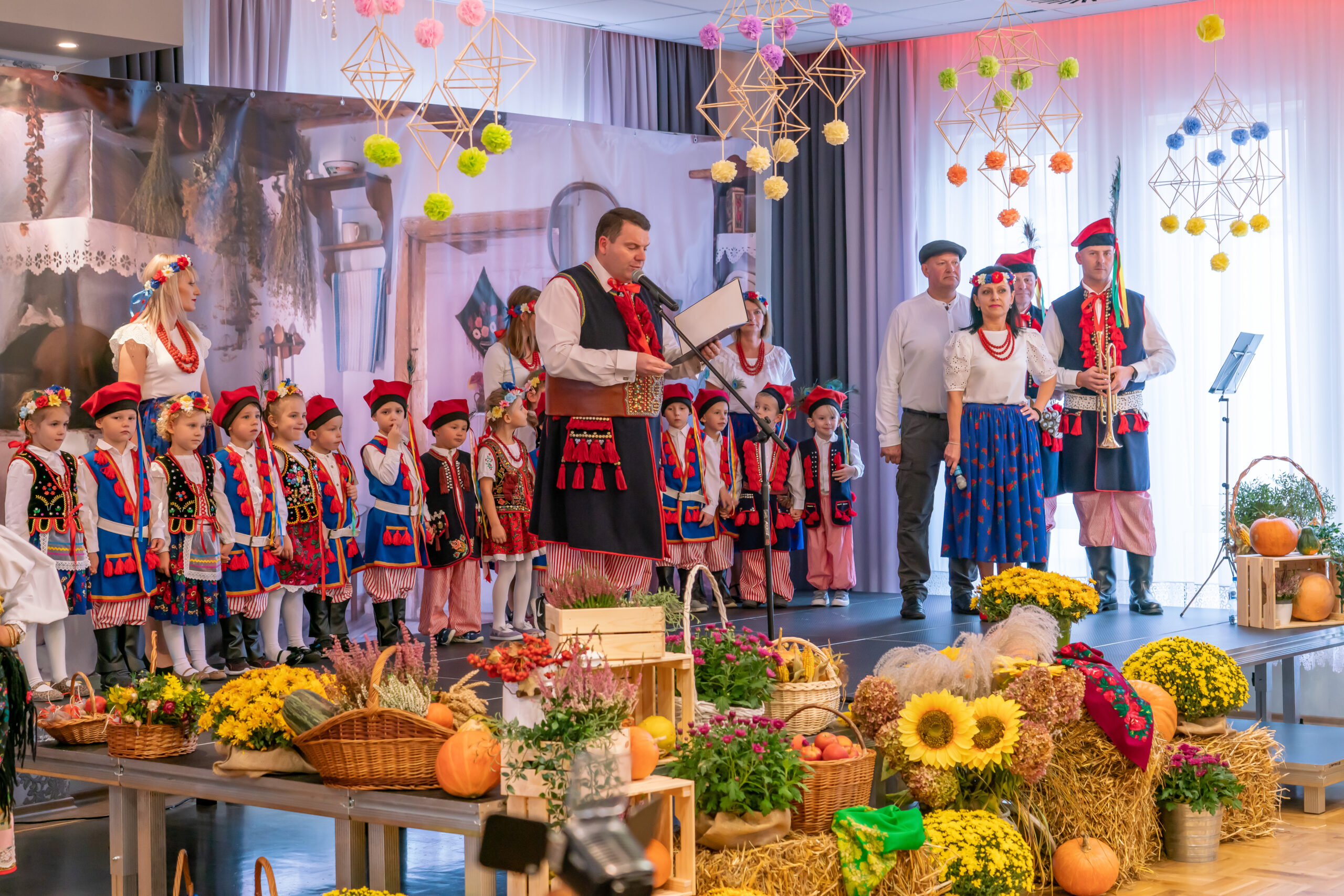 zdjcie przedstawia scenę, na scenie dzieci i dorośli w strojach krakowskich